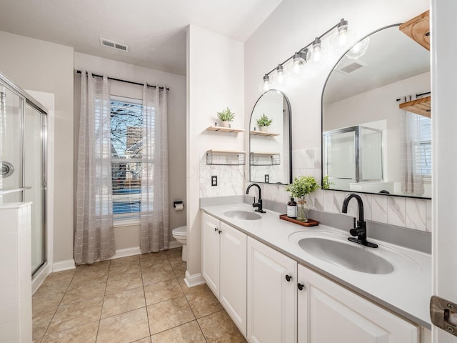 bathroom with toilet, tile patterned flooring, a shower with door, and vanity