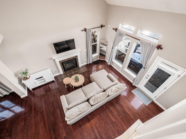 living room featuring high vaulted ceiling, dark hardwood / wood-style flooring, and a tiled fireplace