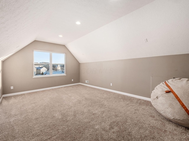 bonus room with vaulted ceiling, a textured ceiling, and carpet flooring