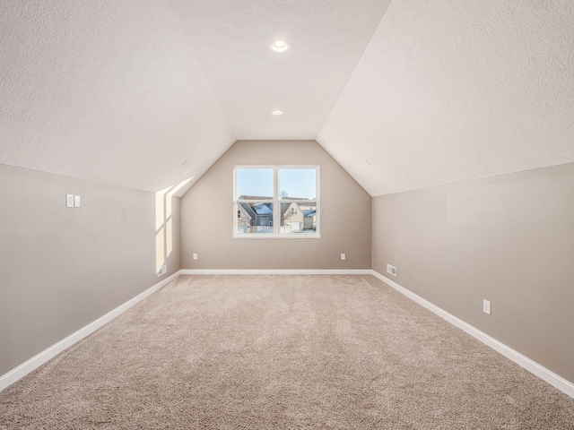 bonus room featuring carpet, vaulted ceiling, and a textured ceiling