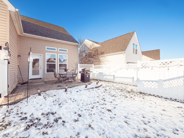 snow covered back of property featuring a patio