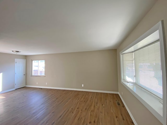 spare room with baseboards, wood finished floors, and visible vents
