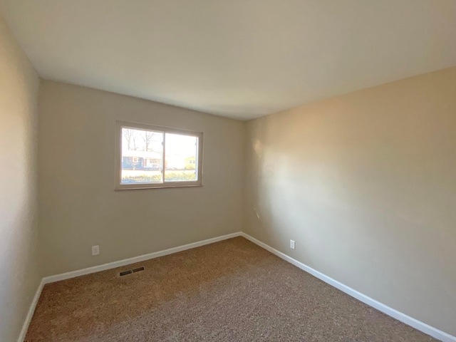 spare room featuring carpet floors and baseboards