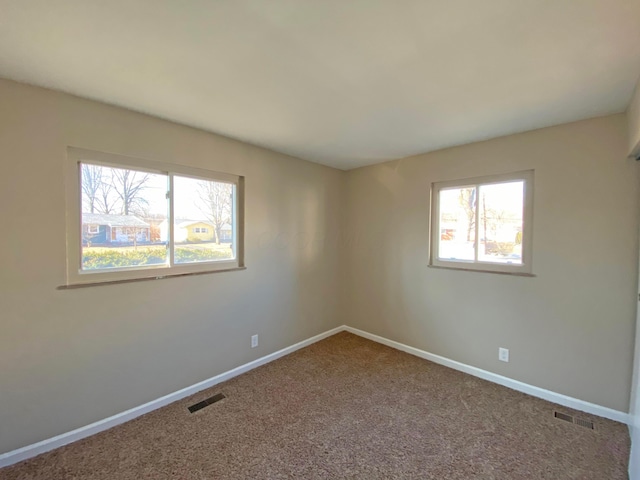 carpeted spare room featuring baseboards and visible vents