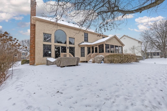 snow covered house featuring a sunroom