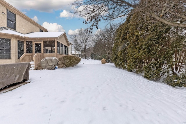 yard layered in snow featuring a sunroom