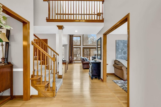 foyer entrance featuring a towering ceiling and light hardwood / wood-style flooring