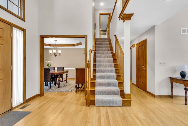 foyer with an inviting chandelier, crown molding, and light hardwood / wood-style flooring