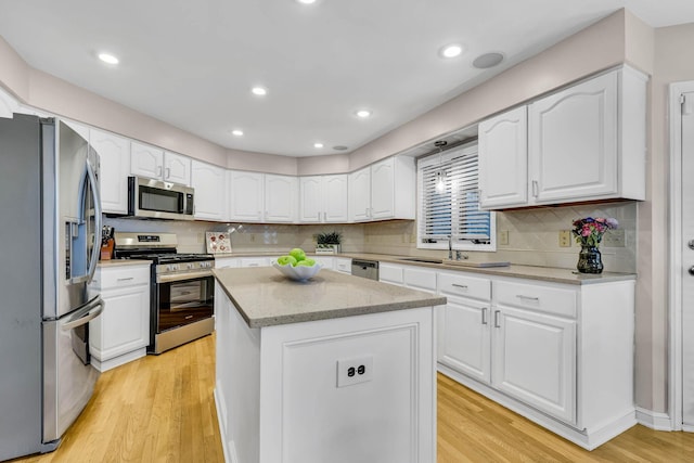 kitchen featuring white cabinets, light wood-type flooring, stainless steel appliances, and a kitchen island