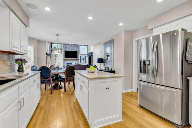 kitchen featuring decorative light fixtures, a center island, white cabinetry, light hardwood / wood-style flooring, and stainless steel fridge with ice dispenser