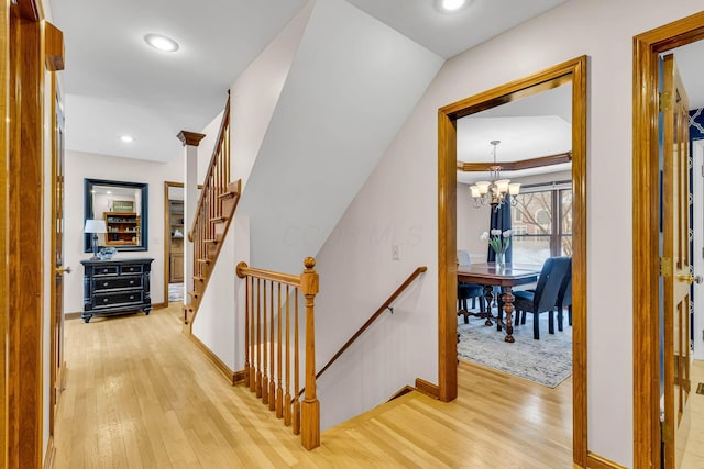 hall with light wood-type flooring and a chandelier