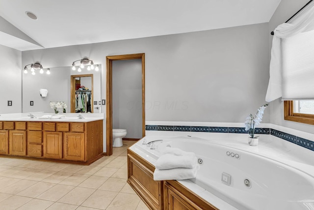 bathroom with tile patterned flooring, vanity, toilet, vaulted ceiling, and a washtub