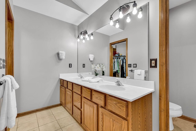 bathroom with vaulted ceiling, vanity, toilet, and tile patterned flooring