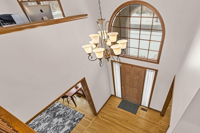 entrance foyer with a high ceiling, an inviting chandelier, and wood-type flooring