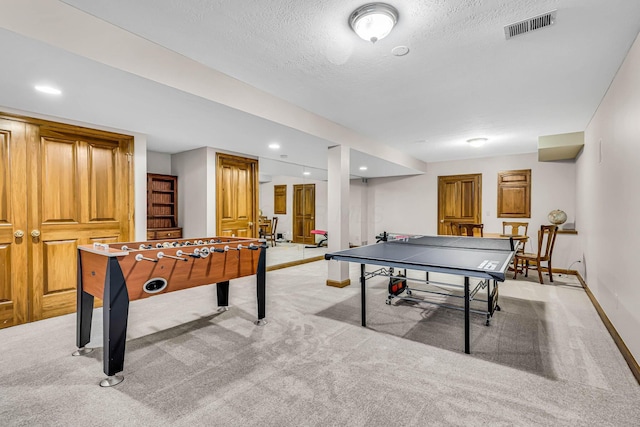 recreation room with a textured ceiling and light carpet