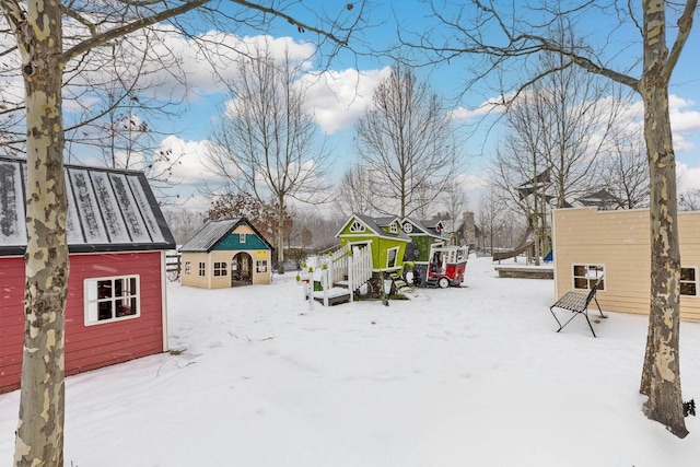 snowy yard featuring an outdoor structure and a playground