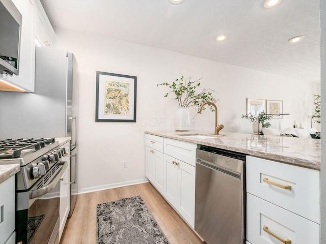 kitchen featuring stainless steel appliances, sink, white cabinets, and light stone counters