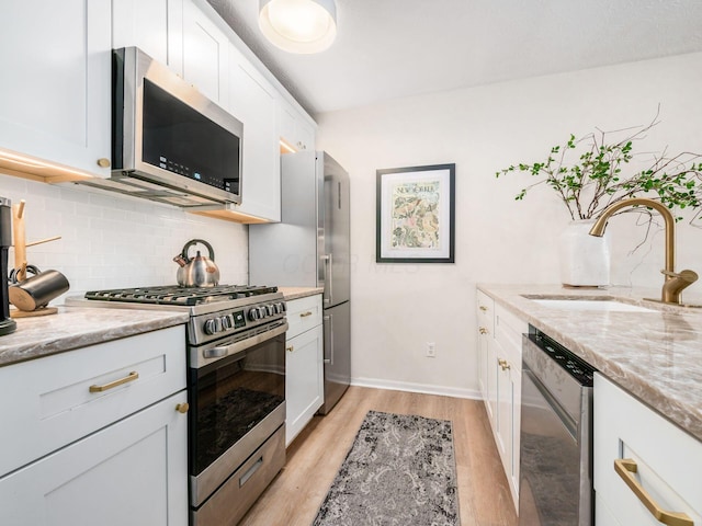 kitchen with light stone counters, sink, stainless steel appliances, and white cabinets