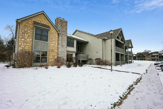 snow covered house featuring a balcony