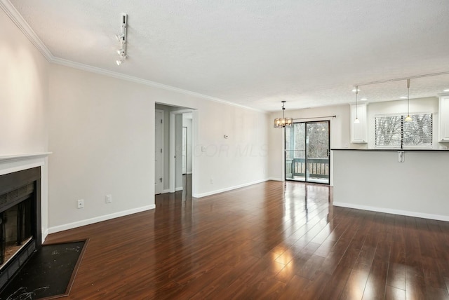 unfurnished living room featuring a chandelier, dark hardwood / wood-style floors, a textured ceiling, and ornamental molding