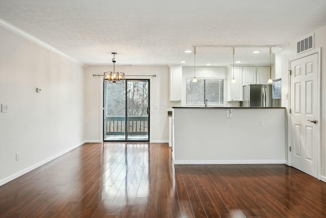 interior space featuring dark wood-type flooring, pendant lighting, white cabinets, and stainless steel refrigerator