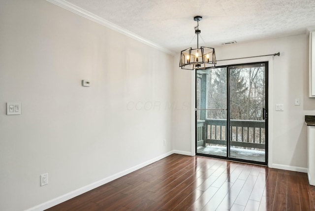 unfurnished room with dark wood-type flooring, a textured ceiling, crown molding, and a notable chandelier