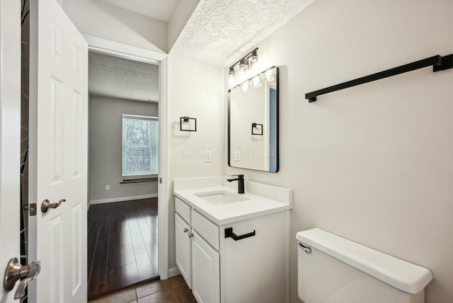 bathroom with tile patterned floors, a textured ceiling, toilet, and vanity