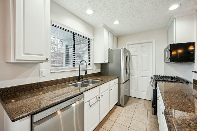 kitchen featuring white cabinetry, stainless steel appliances, dark stone countertops, a textured ceiling, and sink