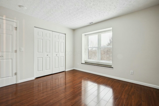 unfurnished bedroom with hardwood / wood-style flooring, a textured ceiling, and a closet