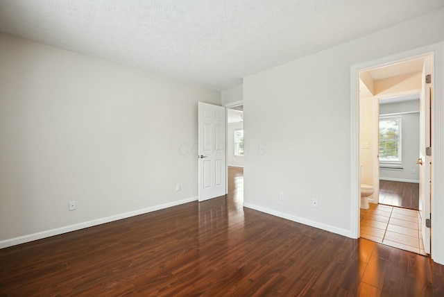 empty room featuring a textured ceiling and dark hardwood / wood-style floors