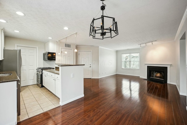 kitchen with appliances with stainless steel finishes, pendant lighting, white cabinetry, and a textured ceiling