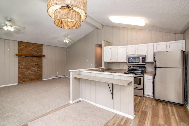 kitchen featuring a textured ceiling, appliances with stainless steel finishes, a kitchen breakfast bar, and white cabinetry