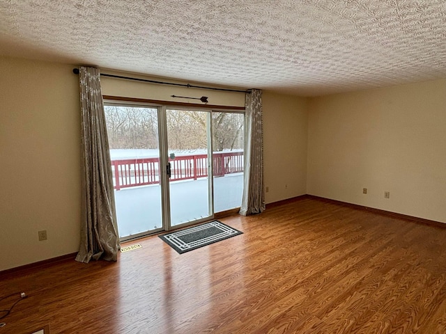 unfurnished room with a textured ceiling and hardwood / wood-style floors