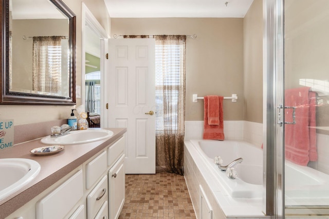 bathroom with a relaxing tiled tub, vanity, and plenty of natural light