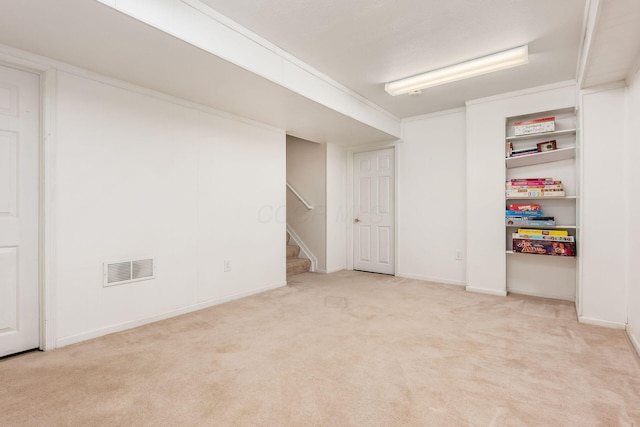 basement with light colored carpet and ornamental molding