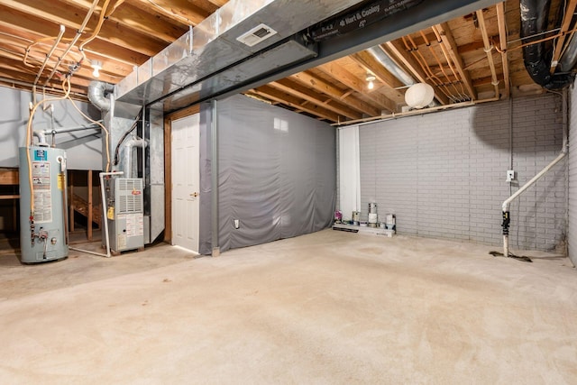 basement featuring brick wall, heating unit, and water heater