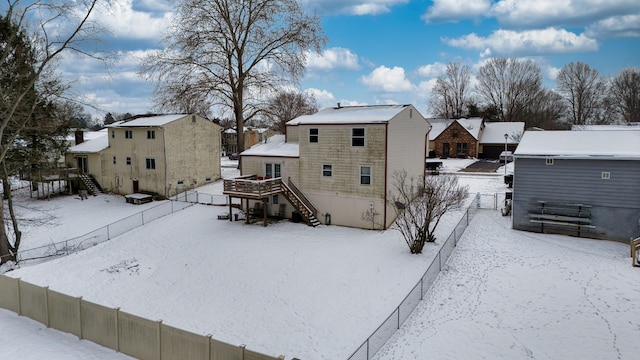 snow covered back of property featuring a deck