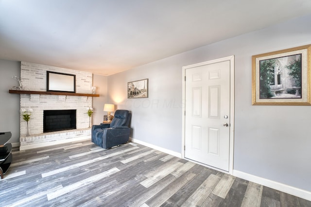 unfurnished room featuring hardwood / wood-style floors and a brick fireplace