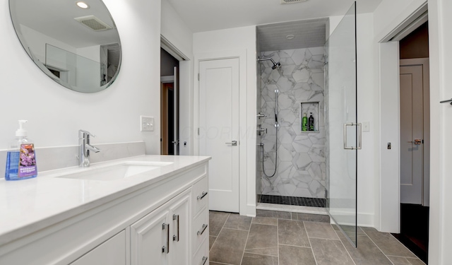 bathroom featuring a tile shower and vanity