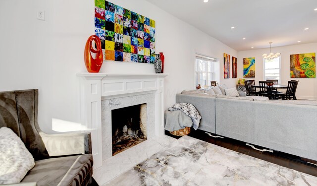 living room with dark hardwood / wood-style floors, a premium fireplace, and an inviting chandelier