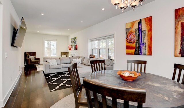 dining area featuring a healthy amount of sunlight, dark wood-type flooring, and an inviting chandelier