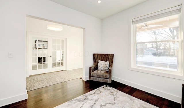 living area with ceiling fan, dark hardwood / wood-style floors, and french doors