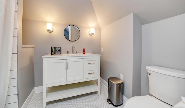 bathroom featuring toilet, vanity, and vaulted ceiling