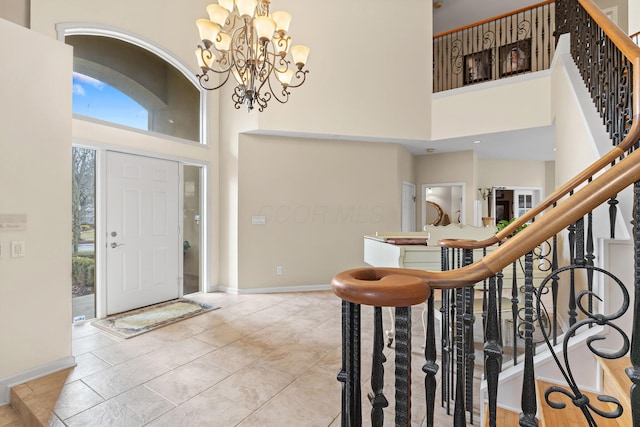 foyer entrance featuring a chandelier, a towering ceiling, baseboards, and stairs