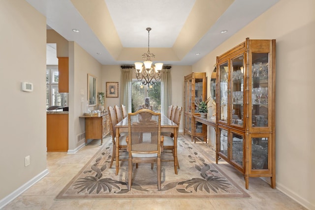 dining room featuring a raised ceiling, visible vents, baseboards, and an inviting chandelier