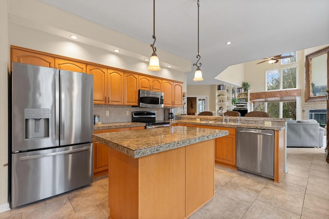 kitchen with stainless steel appliances, a peninsula, a sink, open floor plan, and decorative light fixtures