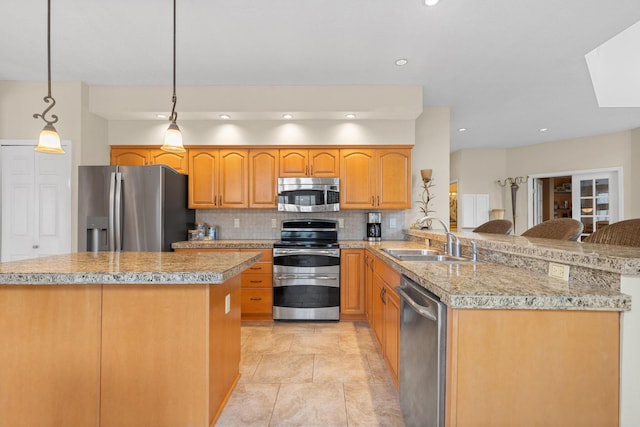 kitchen with decorative light fixtures, a breakfast bar area, stainless steel appliances, a sink, and a peninsula