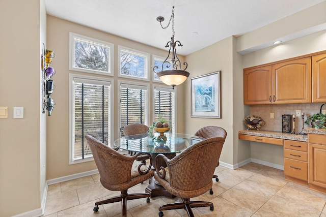 dining space featuring light tile patterned floors, built in desk, and baseboards