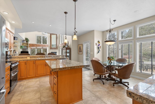 kitchen featuring hanging light fixtures, double oven range, tile counters, and brown cabinets