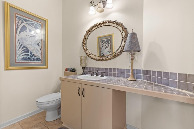 half bathroom with tile patterned flooring, baseboards, vanity, and toilet